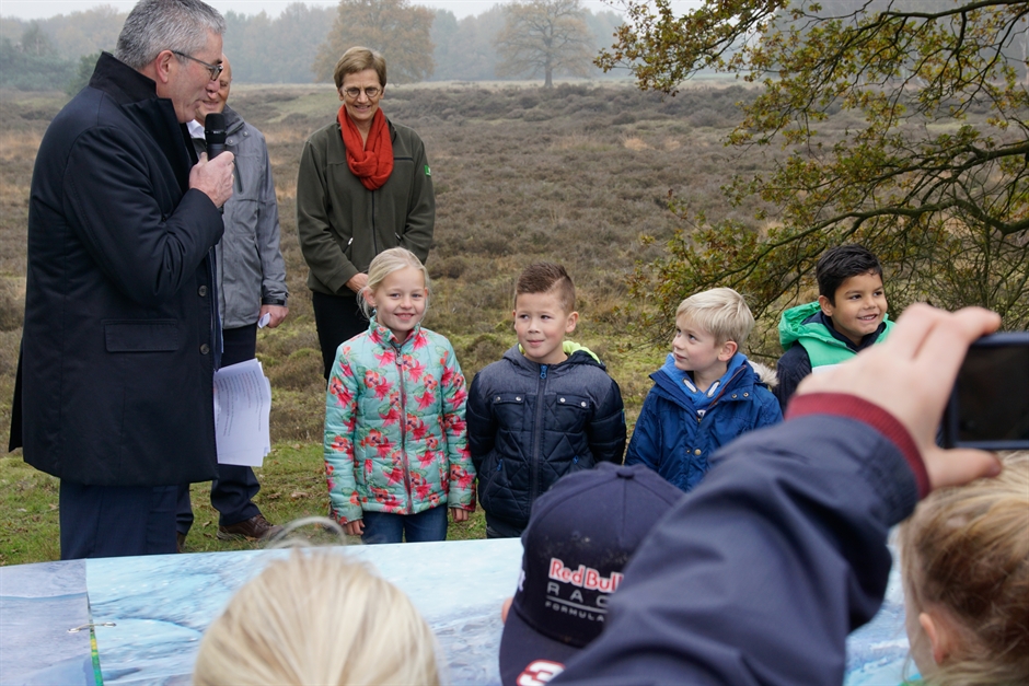 Leerlingen van de basisscholen CBS De Wegwijzer en OBS De Lindelaar uit Westerbork samen met wethouder Gerard Lohuis, gedeputeerde Henk Jumelet en gebiedsmanager Ans van Wijk van Staatsbosbeheer bij het informatiepaneel.